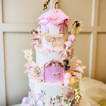 Tall pink fairy-house cake with sugar fairies and flowers