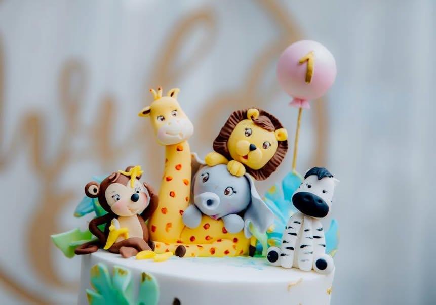 First birthday cake topped with a sugar giraffe, lion, elephant, monkey and zebra