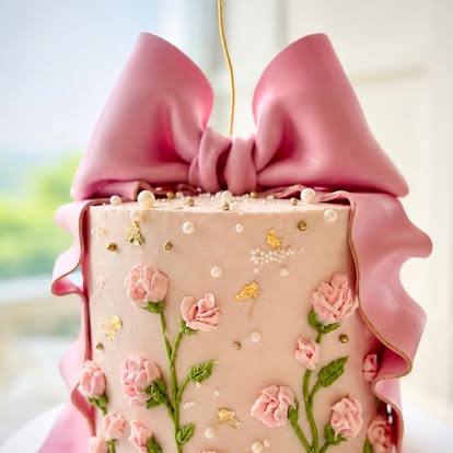 Blush pink cake with piped roses and a large pink sugar bow