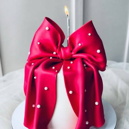 White cake wrapped in a glossy red sugar bow with pearls