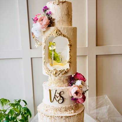 Tall gold-textured tiered cake with a framed window, flowers and initials